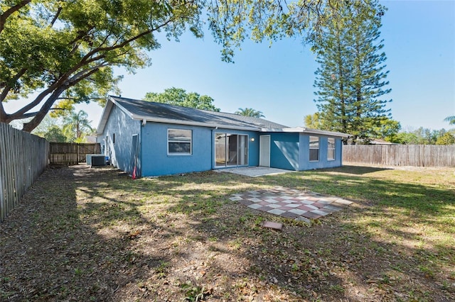 rear view of house featuring central air condition unit, a fenced backyard, a lawn, and stucco siding