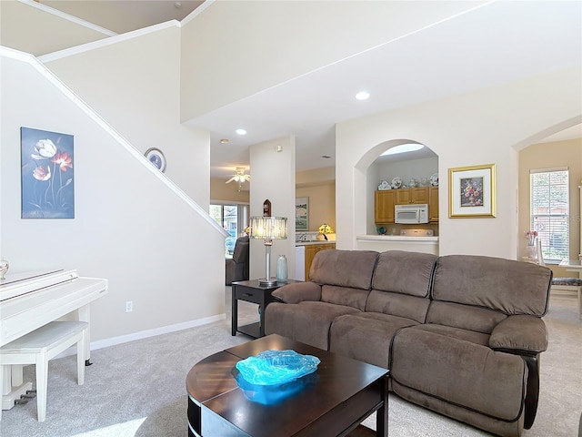 living room featuring stairway, arched walkways, light colored carpet, and a healthy amount of sunlight