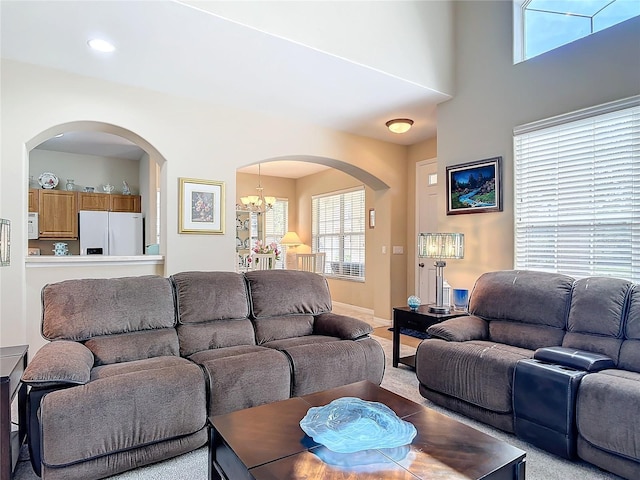 living room with arched walkways, carpet floors, and an inviting chandelier