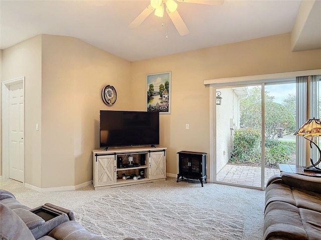 living area featuring carpet flooring, baseboards, a wood stove, and ceiling fan
