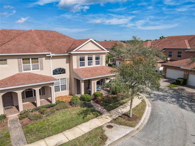 view of front of home with driveway, covered porch, a shingled roof, stucco siding, and a garage