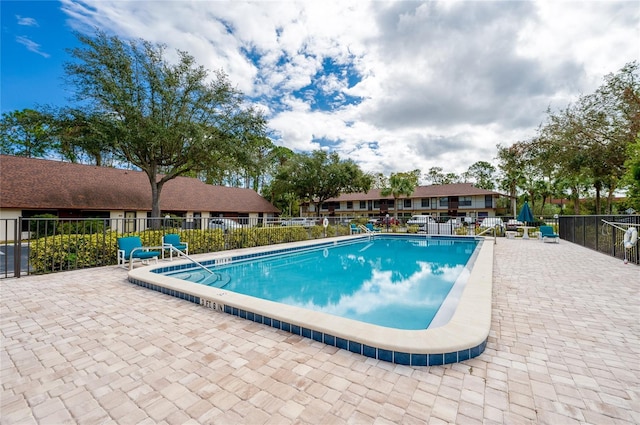 pool with a patio area and fence