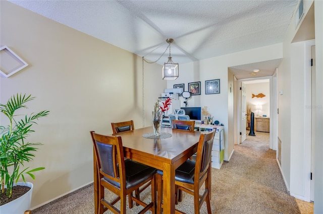 dining room with baseboards, light colored carpet, visible vents, and a textured ceiling