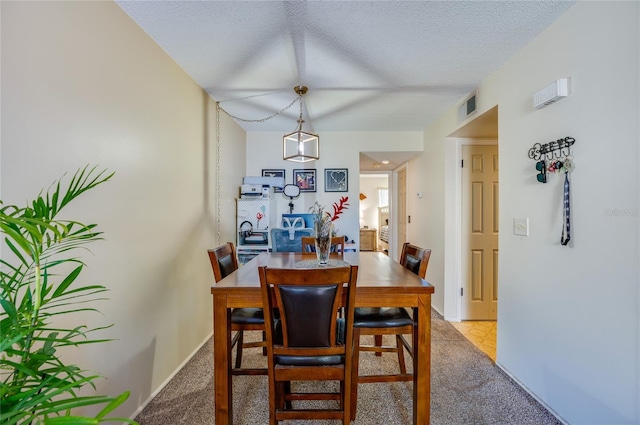 dining room featuring baseboards, visible vents, carpet floors, and a textured ceiling