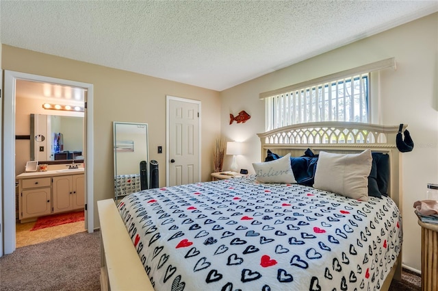 carpeted bedroom featuring ensuite bath, a textured ceiling, and a sink