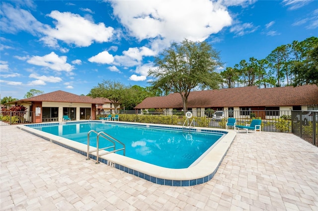 community pool with a patio area and fence