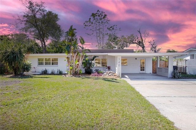 view of front of property featuring driveway, a carport, a front lawn, and fence