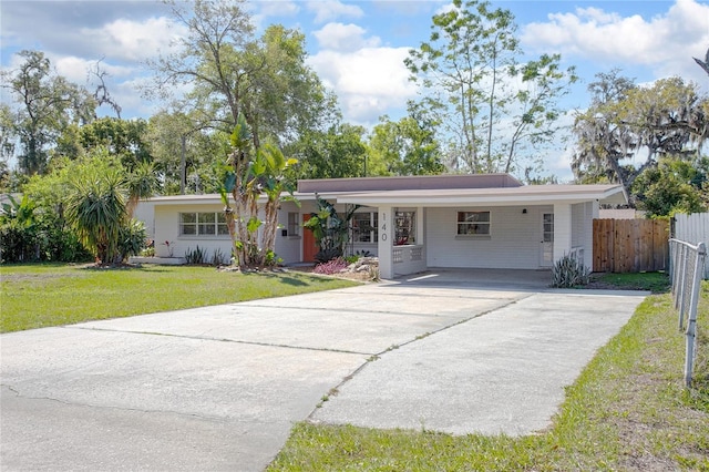 ranch-style house with concrete driveway, fence, a carport, and a front yard