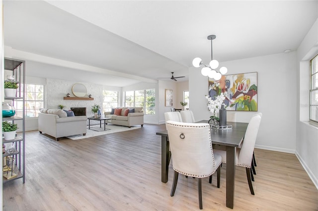 dining space featuring plenty of natural light, a fireplace, light wood-type flooring, and baseboards