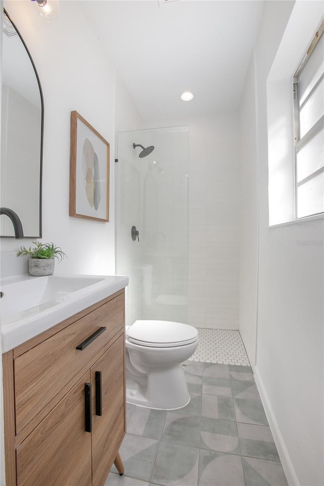 full bathroom featuring tiled shower, toilet, and vanity