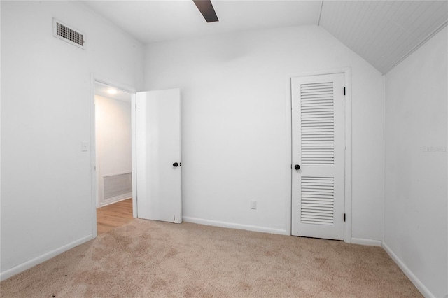 unfurnished bedroom with lofted ceiling, carpet flooring, baseboards, and visible vents