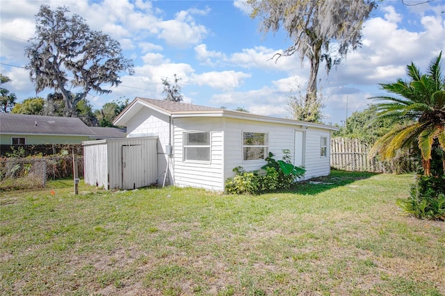 exterior space featuring an outdoor structure, a storage unit, a lawn, and fence