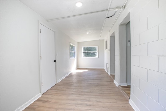 hallway with light wood-type flooring and baseboards