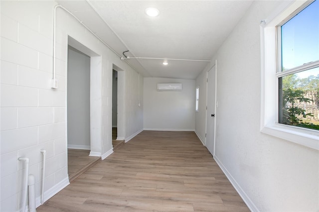 hallway with recessed lighting, baseboards, light wood-style floors, and a wall mounted AC