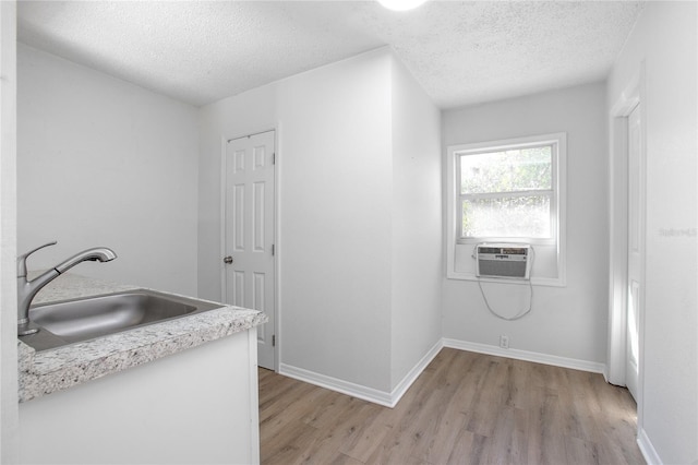 interior space with light wood-type flooring, a sink, cooling unit, light countertops, and baseboards