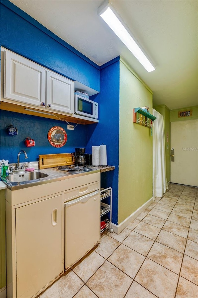 kitchen with white microwave, light countertops, light tile patterned floors, white cabinetry, and a sink