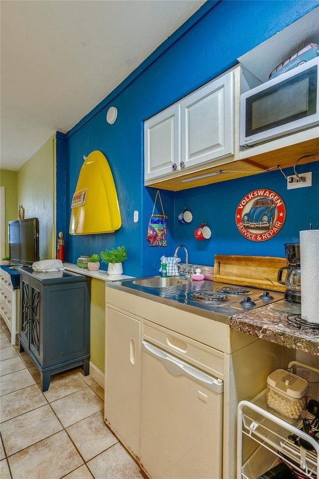 kitchen featuring white microwave, light tile patterned floors, and white cabinets