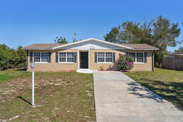 ranch-style house with brick siding, driveway, a front yard, and fence