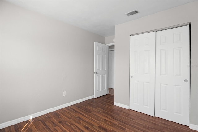 unfurnished bedroom featuring a closet, baseboards, visible vents, and dark wood-style flooring