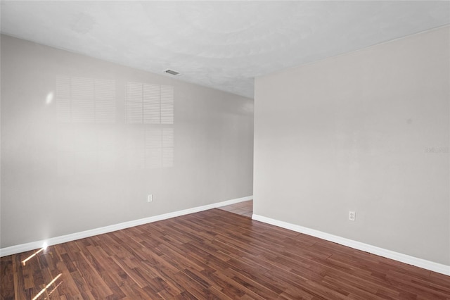 spare room with visible vents, baseboards, and wood finished floors