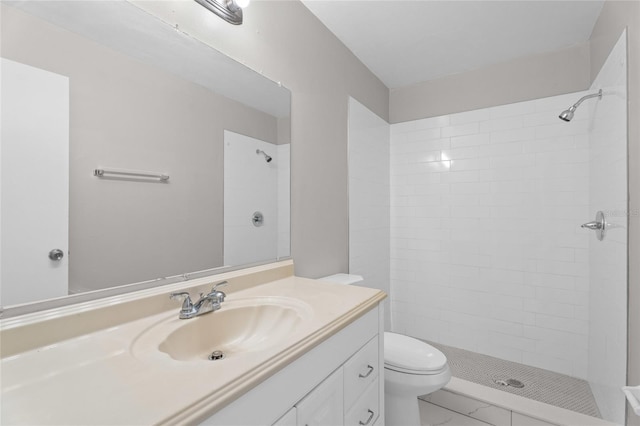 full bathroom featuring tiled shower, toilet, and vanity