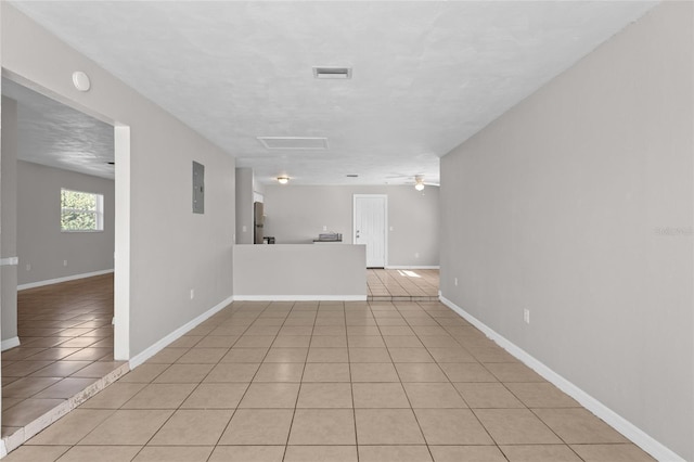 unfurnished living room with light tile patterned floors, baseboards, electric panel, and a ceiling fan