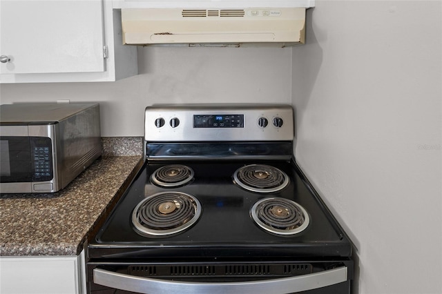 interior details with range with electric cooktop, stainless steel microwave, dark countertops, white cabinetry, and ventilation hood