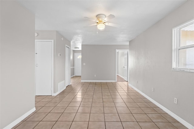 spare room featuring light tile patterned floors, baseboards, and ceiling fan