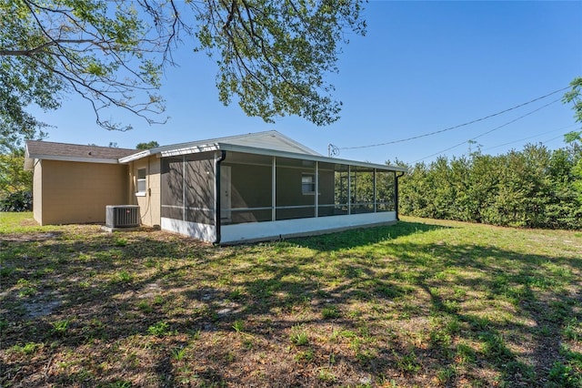 rear view of property featuring a lawn, central AC, and a sunroom