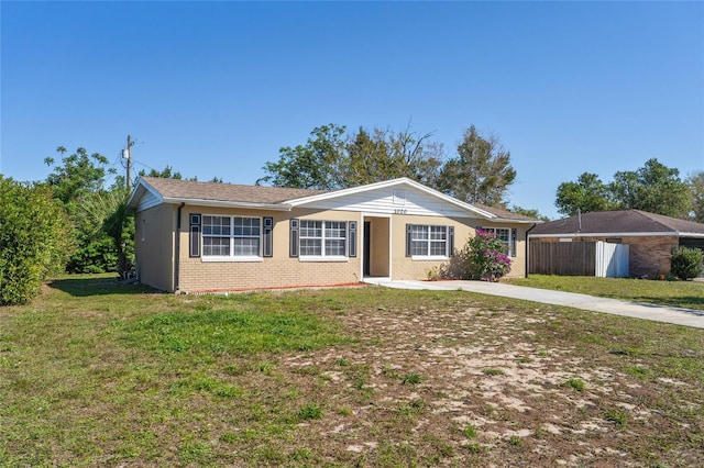 single story home with brick siding, driveway, a front lawn, and fence