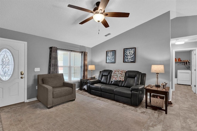 living area with visible vents, a ceiling fan, baseboards, washer / dryer, and vaulted ceiling