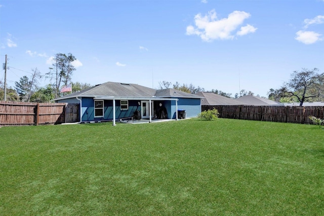 rear view of property featuring a yard and a fenced backyard