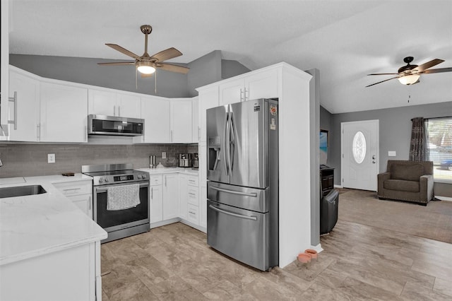 kitchen with light stone counters, open floor plan, appliances with stainless steel finishes, ceiling fan, and vaulted ceiling