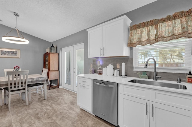 kitchen with a sink, stainless steel dishwasher, white cabinetry, light countertops, and vaulted ceiling