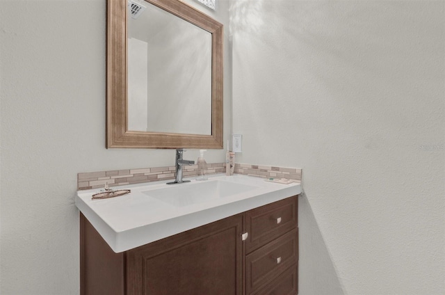 bathroom with visible vents, backsplash, and vanity