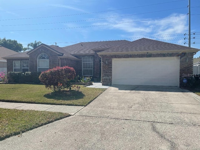 single story home with roof with shingles, concrete driveway, an attached garage, a front yard, and brick siding