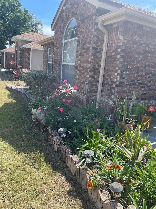 view of side of property featuring brick siding and a lawn