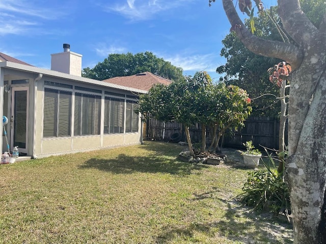 view of yard featuring a sunroom and fence