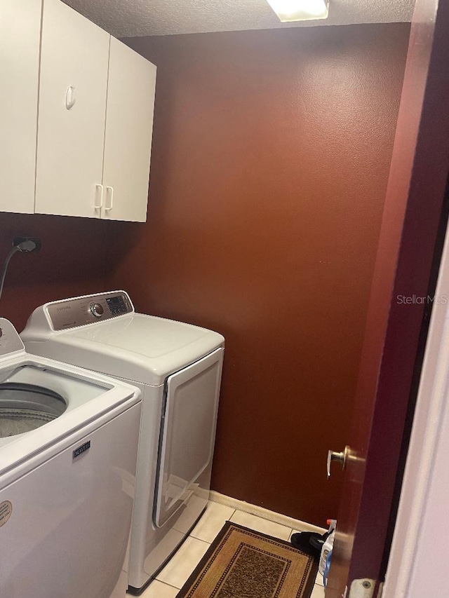 laundry area with light tile patterned floors, washing machine and dryer, and cabinet space