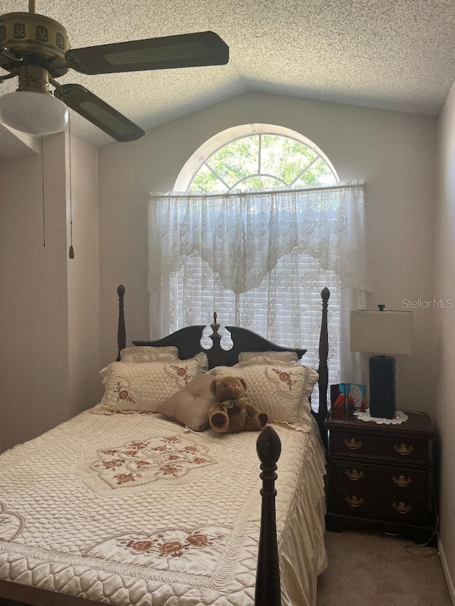 bedroom with a textured ceiling, vaulted ceiling, carpet, and ceiling fan