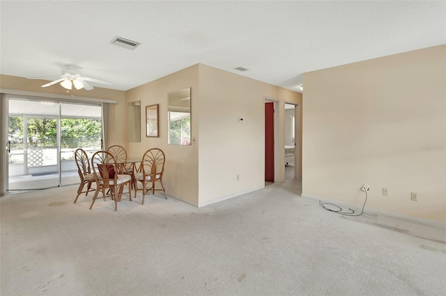 carpeted dining area featuring visible vents, baseboards, a textured ceiling, and a ceiling fan