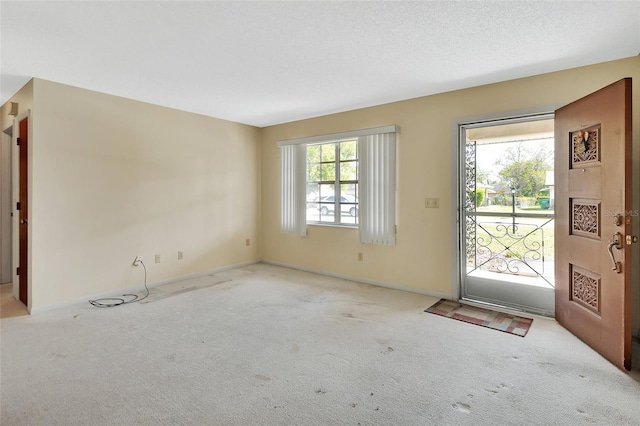 entryway with baseboards, a textured ceiling, and carpet