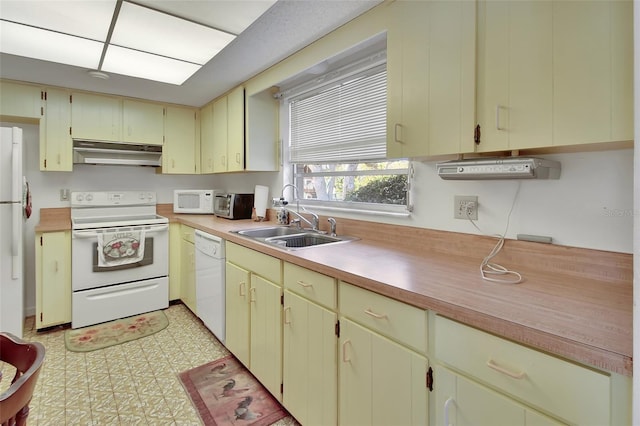 kitchen with under cabinet range hood, white appliances, light countertops, and a sink