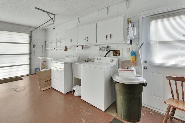 washroom with concrete block wall, cabinet space, a sink, a textured ceiling, and independent washer and dryer