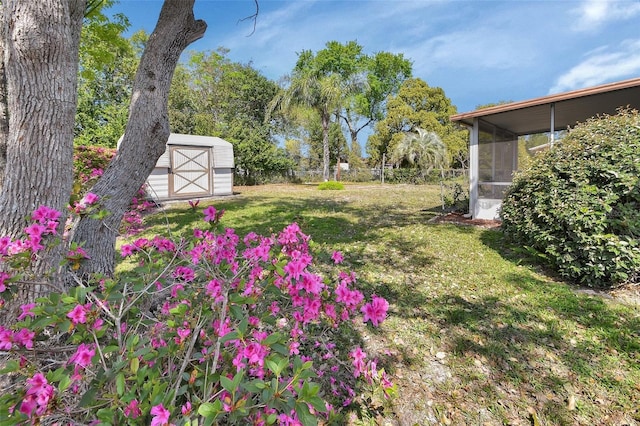 view of yard featuring a sunroom, fence, an outdoor structure, and a shed