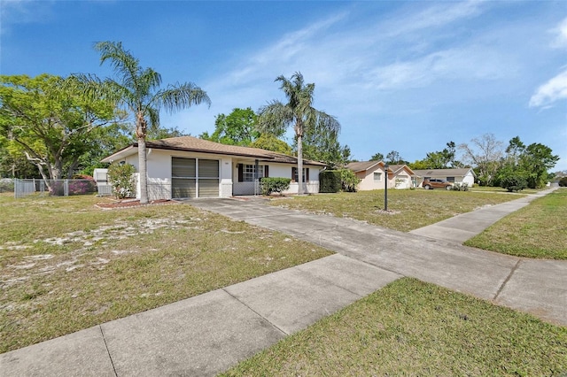 view of front of property with a garage, concrete driveway, a front lawn, and fence