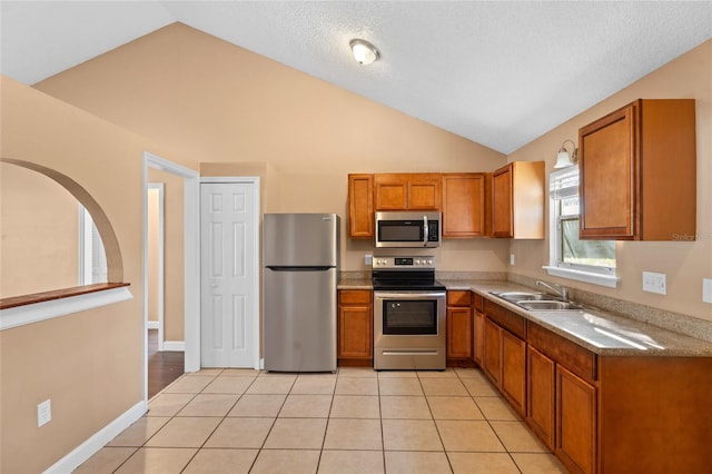 kitchen featuring light tile patterned floors, brown cabinets, appliances with stainless steel finishes, and a sink