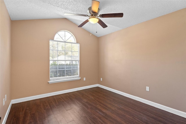 spare room featuring dark wood-type flooring, lofted ceiling, a ceiling fan, a textured ceiling, and baseboards