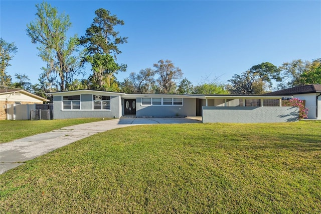 mid-century home with stucco siding, a front yard, driveway, and fence