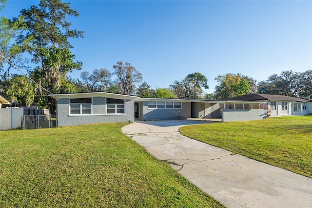 mid-century modern home with a front lawn, fence, concrete driveway, stucco siding, and a carport